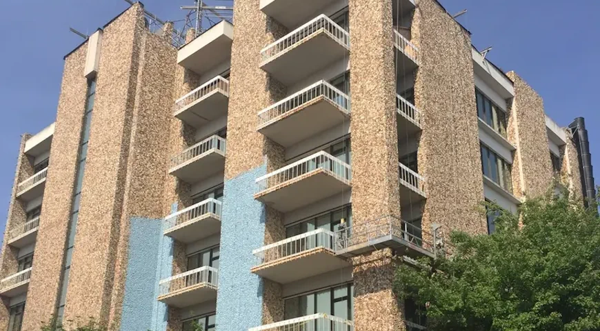 Old stone building with balconies and scaffolding during application of Dryvit Backstop NT. 